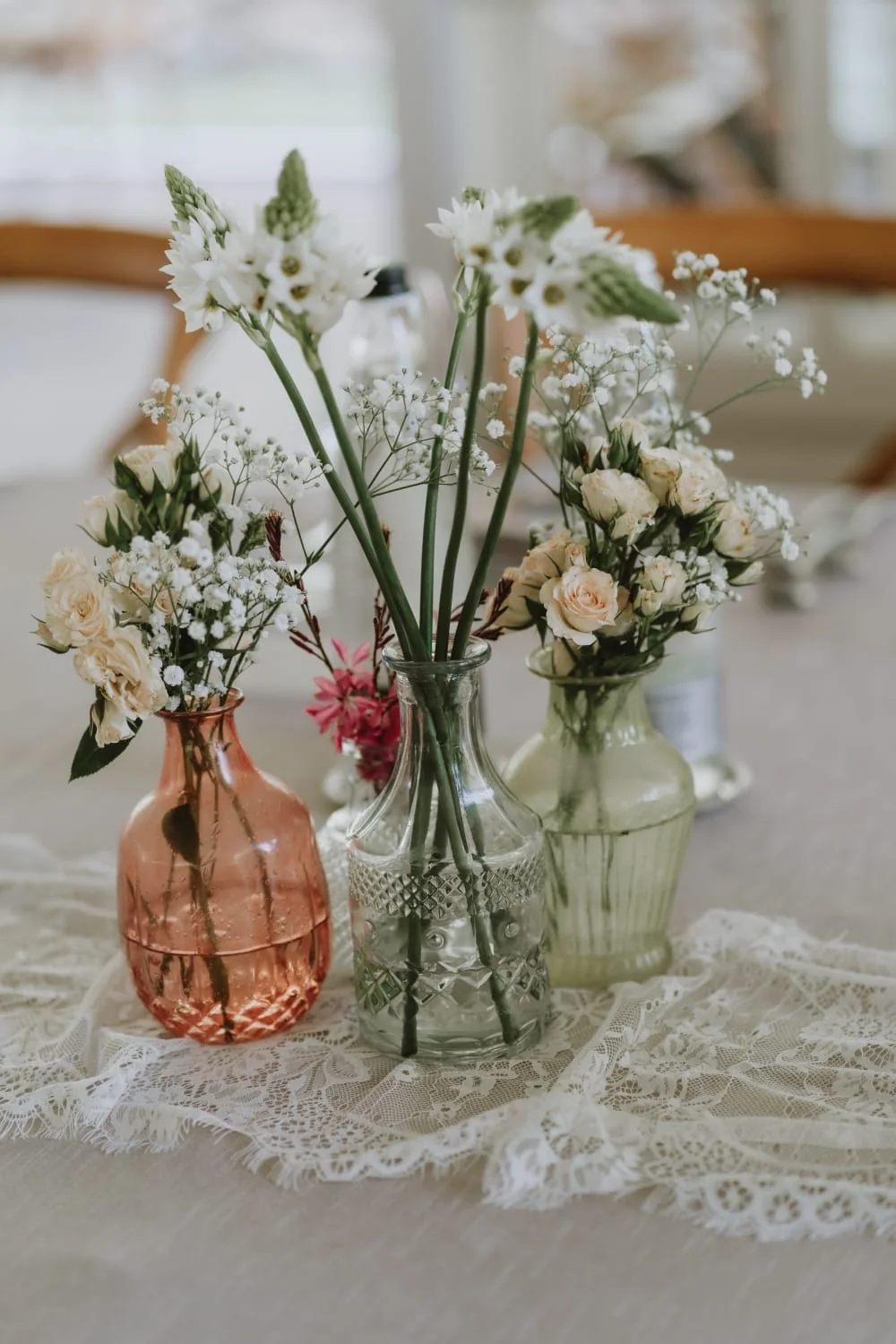 Vasi in vetro colorato con piccoli bouquet di fiori bianchi